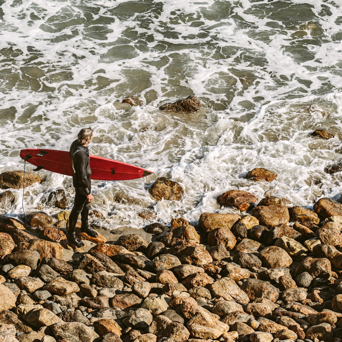Surfista observando el mar antes de una sesión en Point Dume, Malibu; fotografía real de Vladimir Kudinov usada en THE SURF TOWN JOURNAL