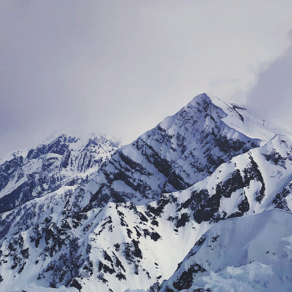 Snowboarder sobre una cresta nevada ajustando su equipo