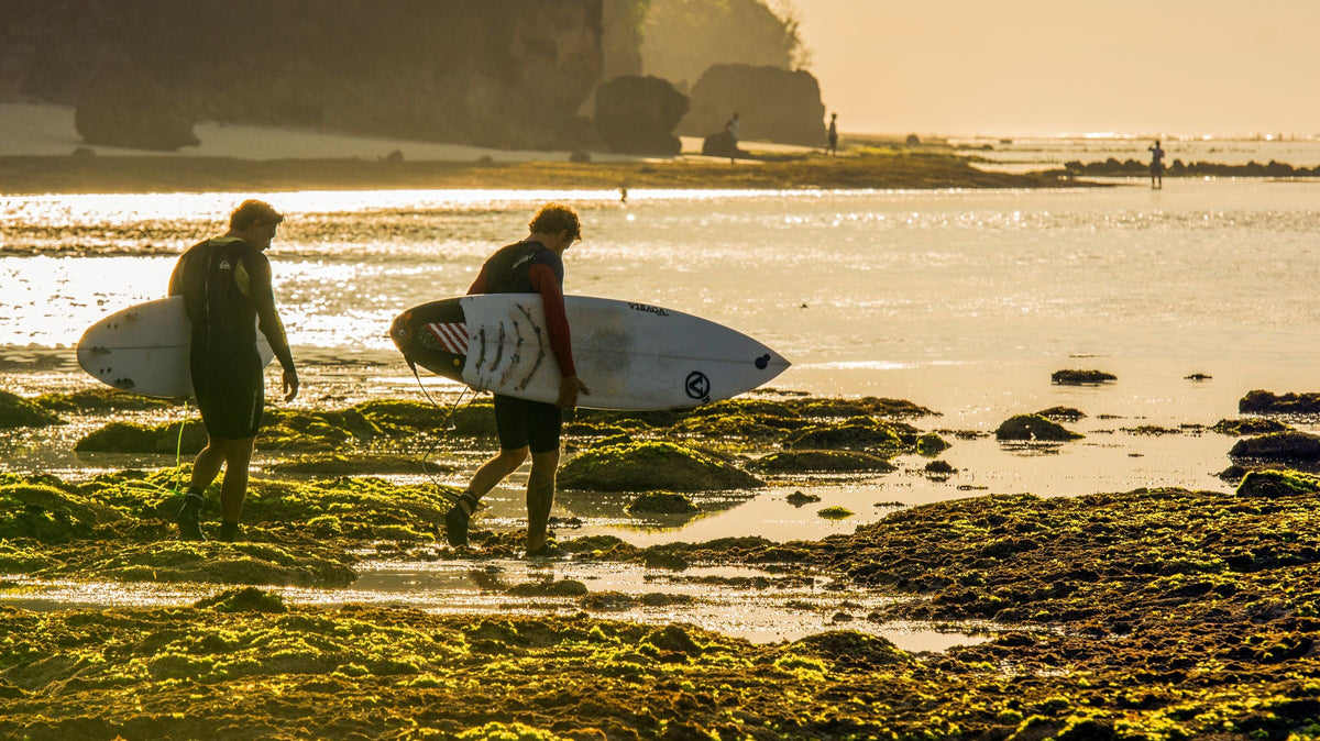 Dos surfistas caminan hacia el mar al amanecer en Bali