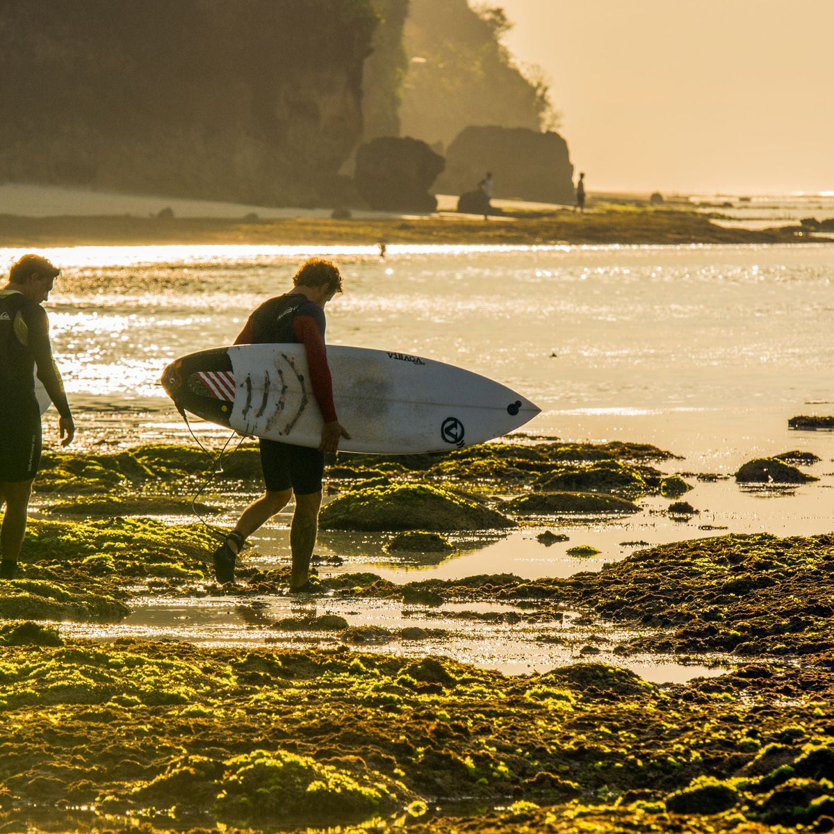 Dos surfistas caminan hacia el mar al amanecer en Bali