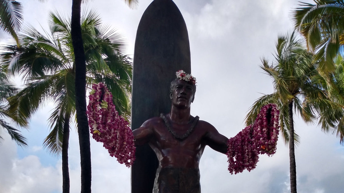 Duke Kahanamoku sobre una tabla de surf en fotografía histórica