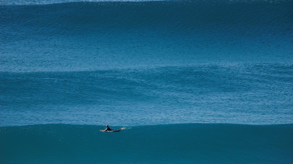 Surfista remando entre líneas de olas durante una sesión en el mar. Foto: bigwavephoto / Wikimedia Commons, CC BY-SA 4.0.