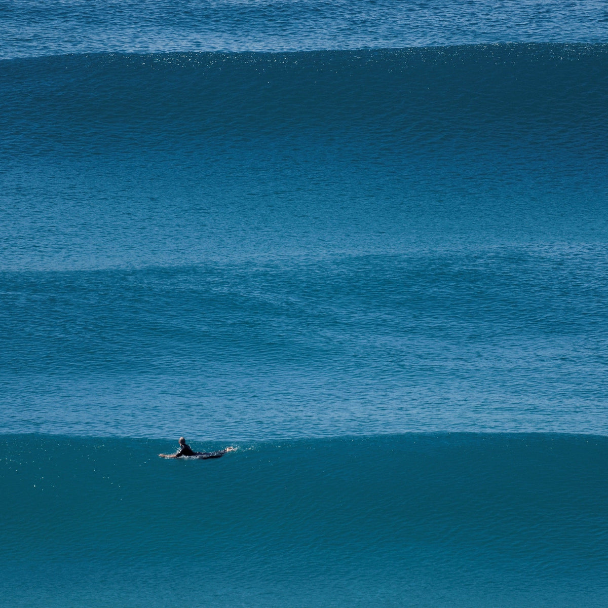Surfista remando entre líneas de olas durante una sesión en el mar. Foto: bigwavephoto / Wikimedia Commons, CC BY-SA 4.0.