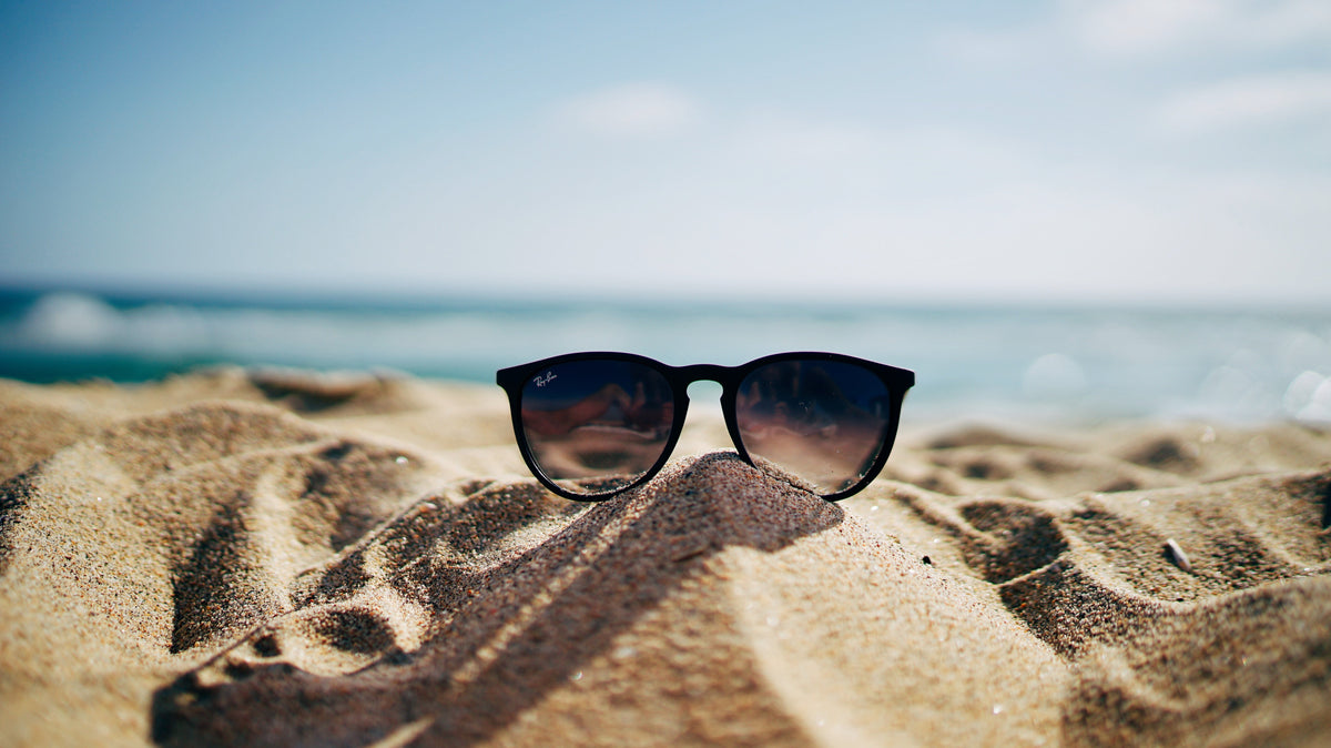 Gafas de sol negras sobre la arena de una playa