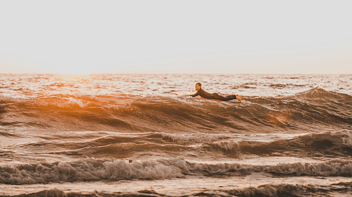 Surfista sobre una ola durante el amanecer