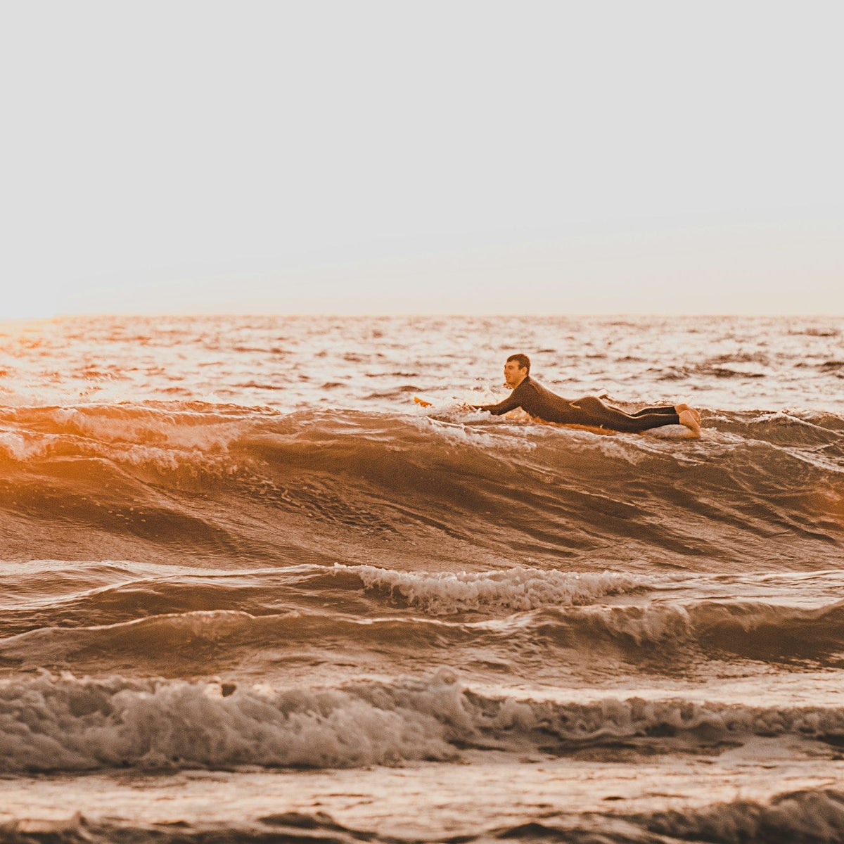 Surfista sobre una ola durante el amanecer