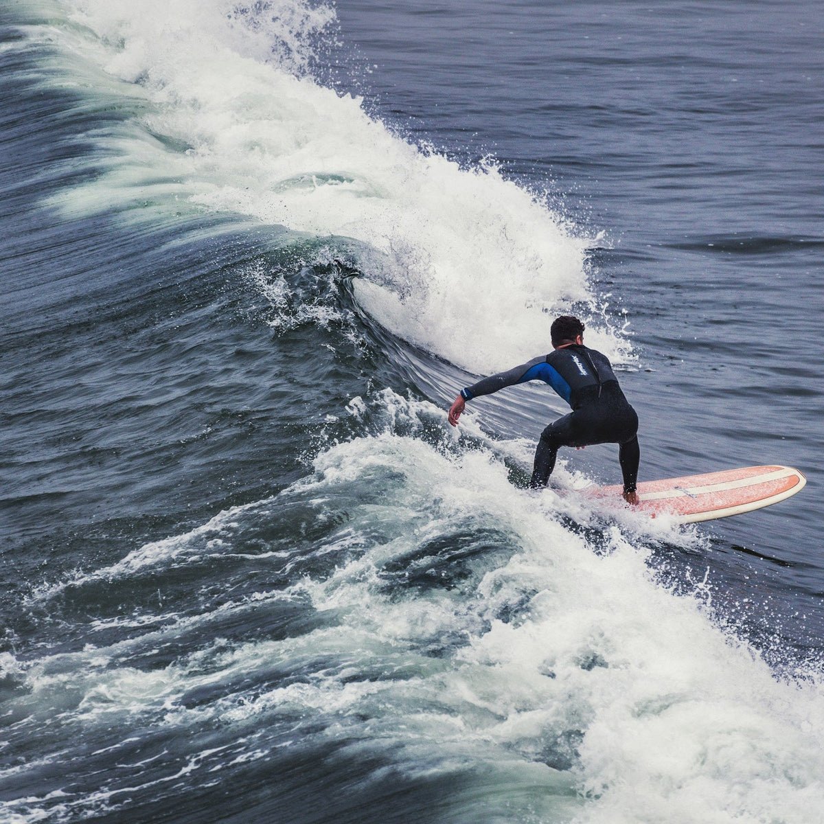 Surfista con traje de neopreno negro recorriendo una ola en Pismo Beach