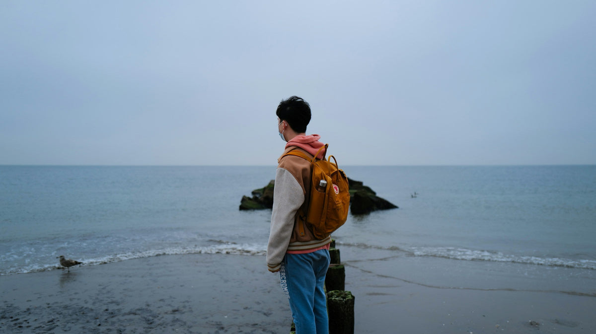 Viajero con mochila frente al mar durante una escapada costera