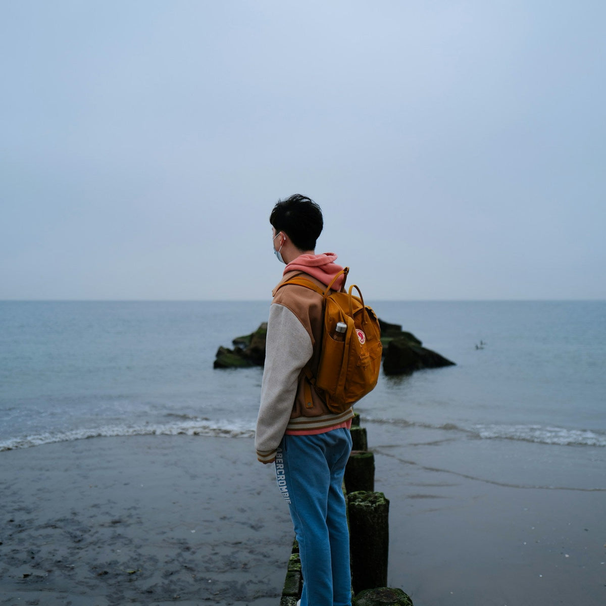 Viajero con mochila frente al mar durante una escapada costera