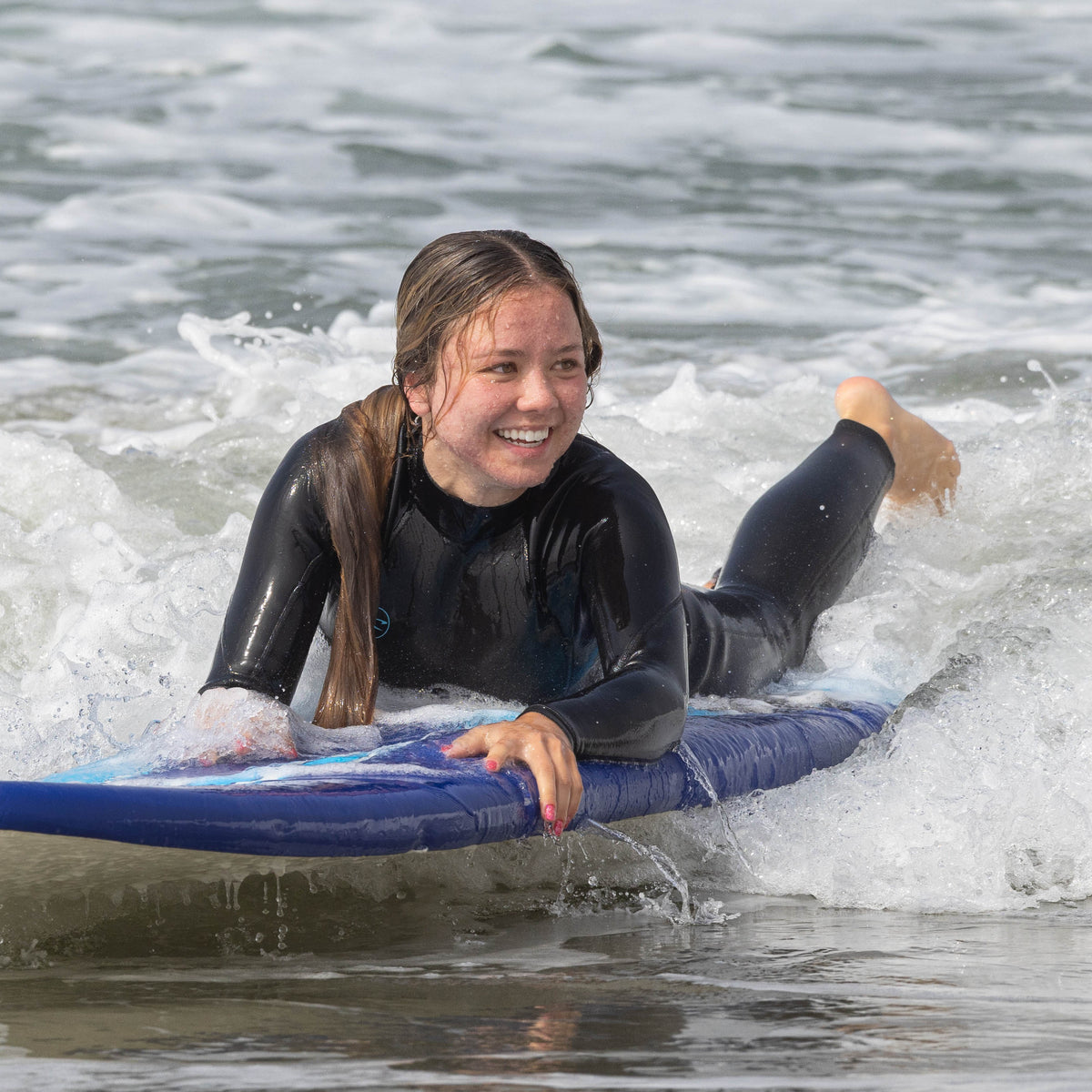 Surfista con traje de neopreno caminando por la playa de Zuma