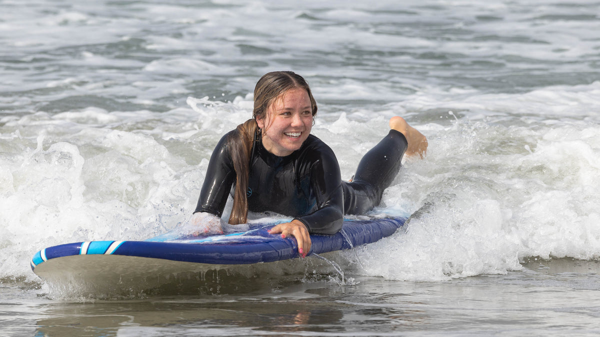 Surfista con traje de neopreno caminando por la playa de Zuma