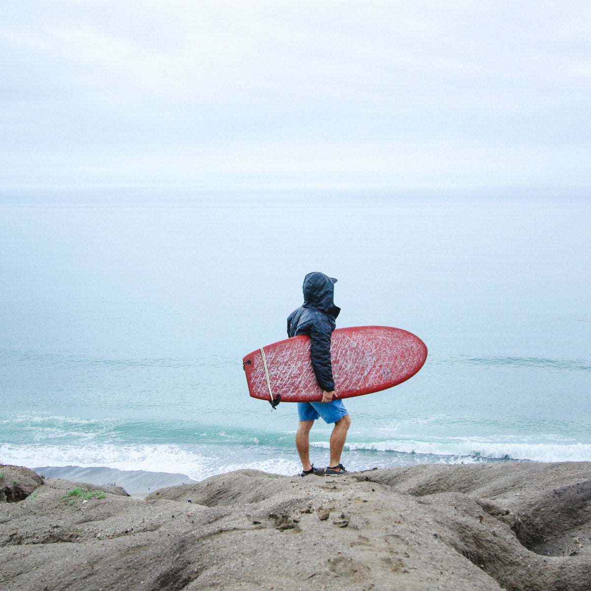 Surfista con capucha de neopreno frente al mar en San Clemente