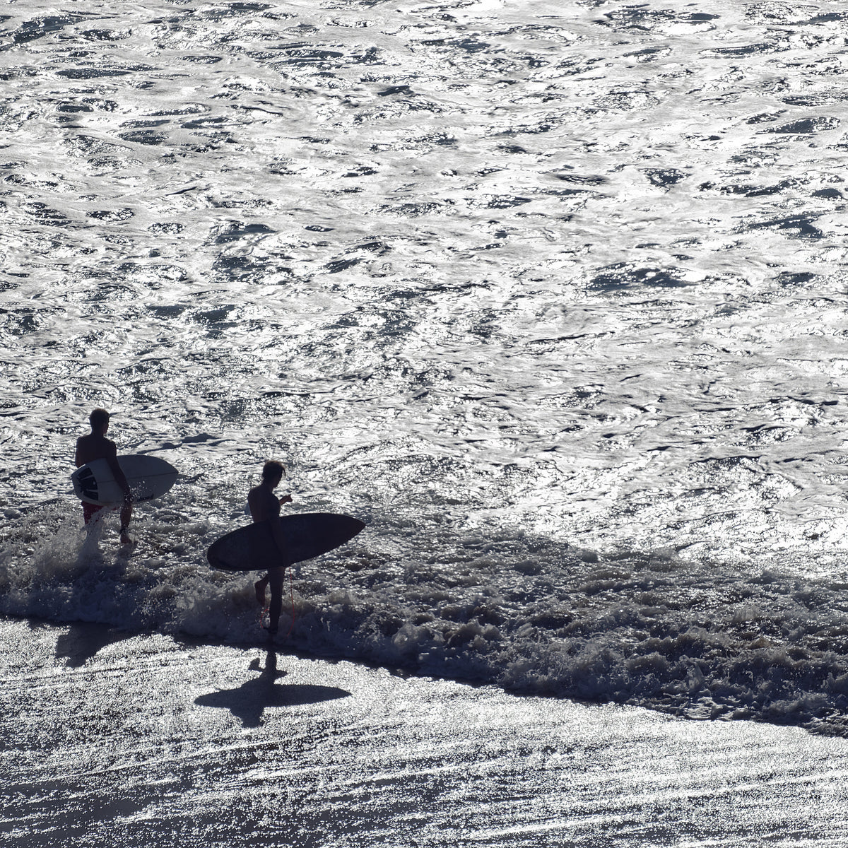 Dos surfistas entrando al agua con luz de amanecer