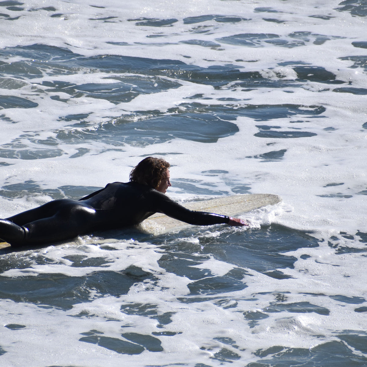 Surfista remando hacia una serie de olas