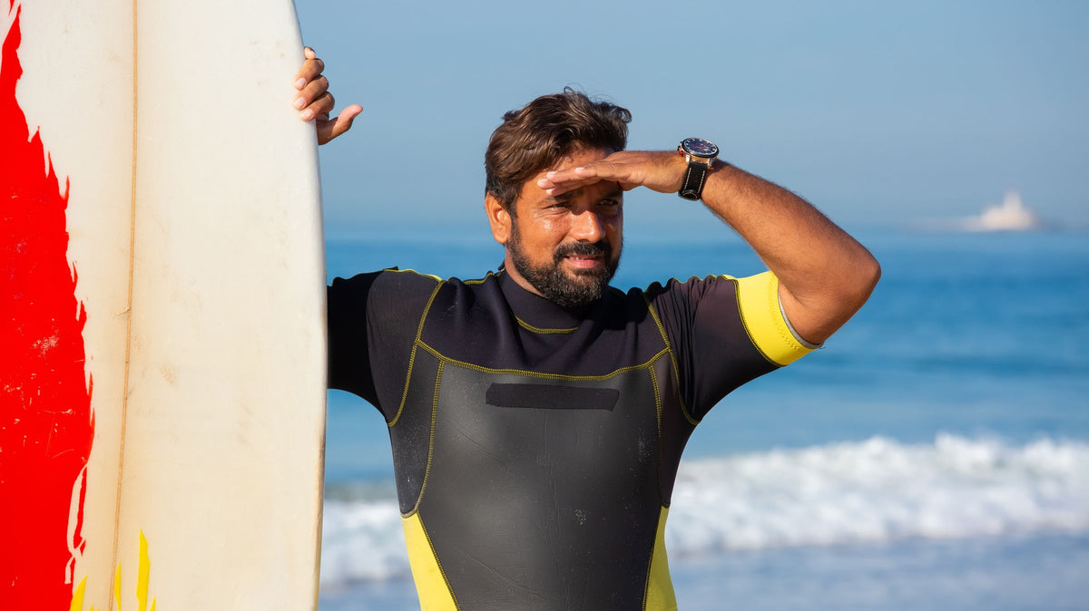 Surfista con traje de neopreno y tabla en una playa de Portugal