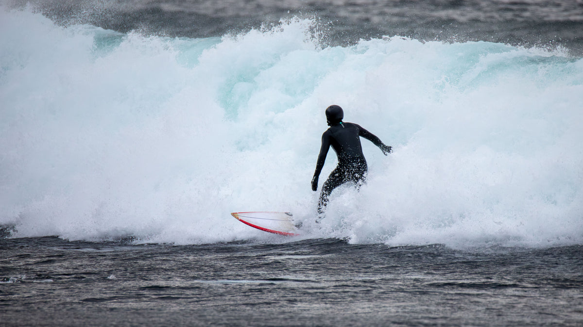 Surfista con neopreno en olas frías de invierno en Noruega