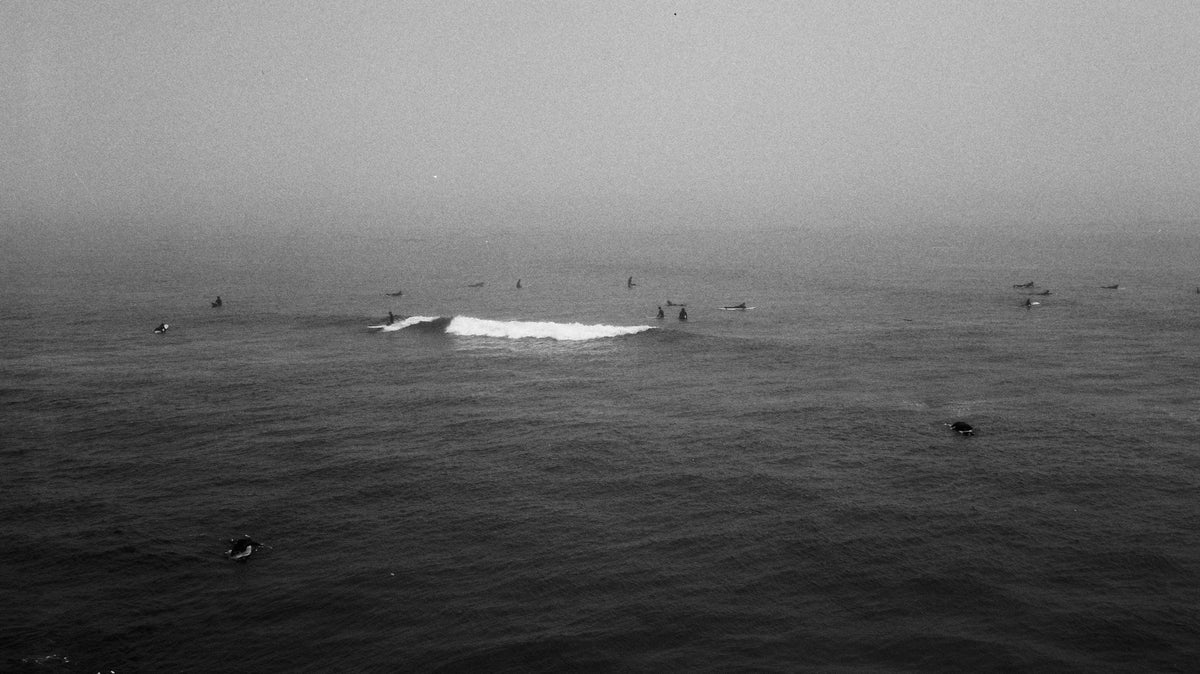 Surfistas entre olas con niebla densa sobre el océano