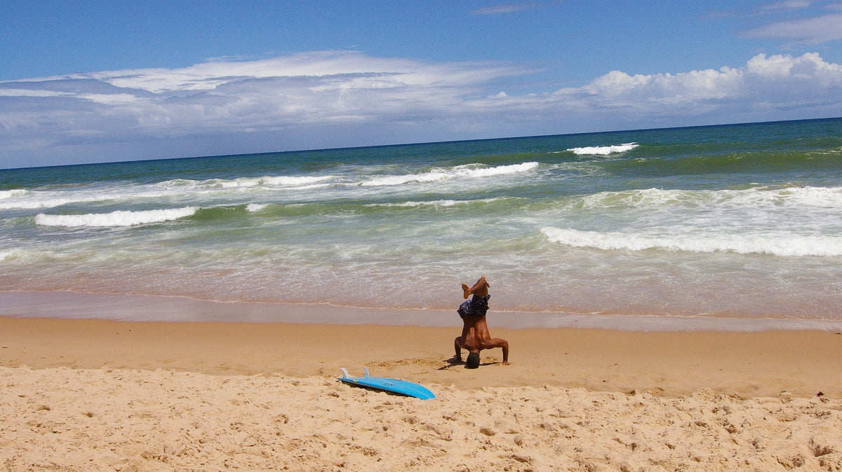 Surfista realizando un calentamiento dinámico en una playa de Bahía antes de entrar al agua