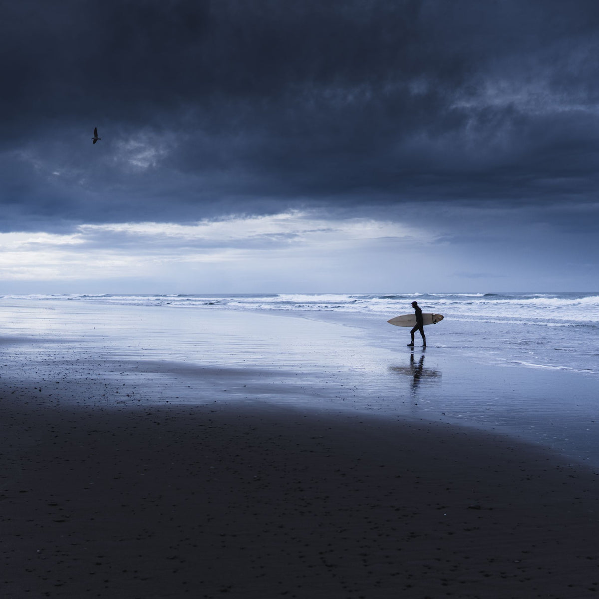 Surfero en una playa bajo nubes de tormenta