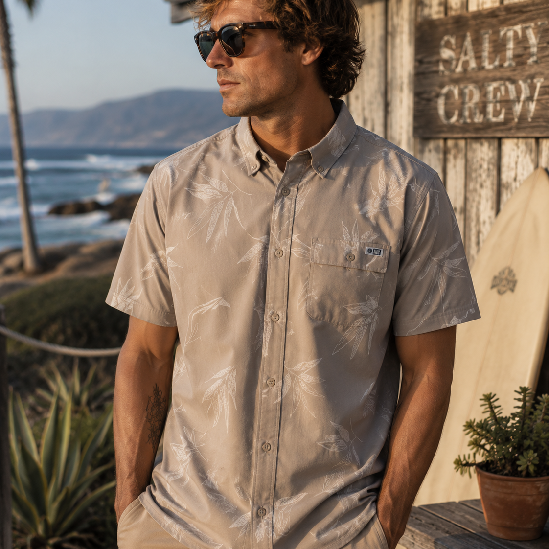 Camisa hombre microperforada Salty Crew color dark khaki en entorno surf shack premium junto al mar estilo lifestyle Costa del Sol