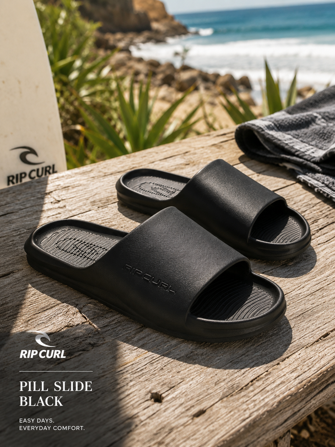 Chanclas de pala Rip Curl Pill Slide Black en escena lifestyle surf sobre madera frente al mar con luz natural de verano
