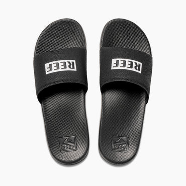 Chanclas de pala REEF One Slide Black White con suela EVA ligera y logo REEF blanco estilo surf verano