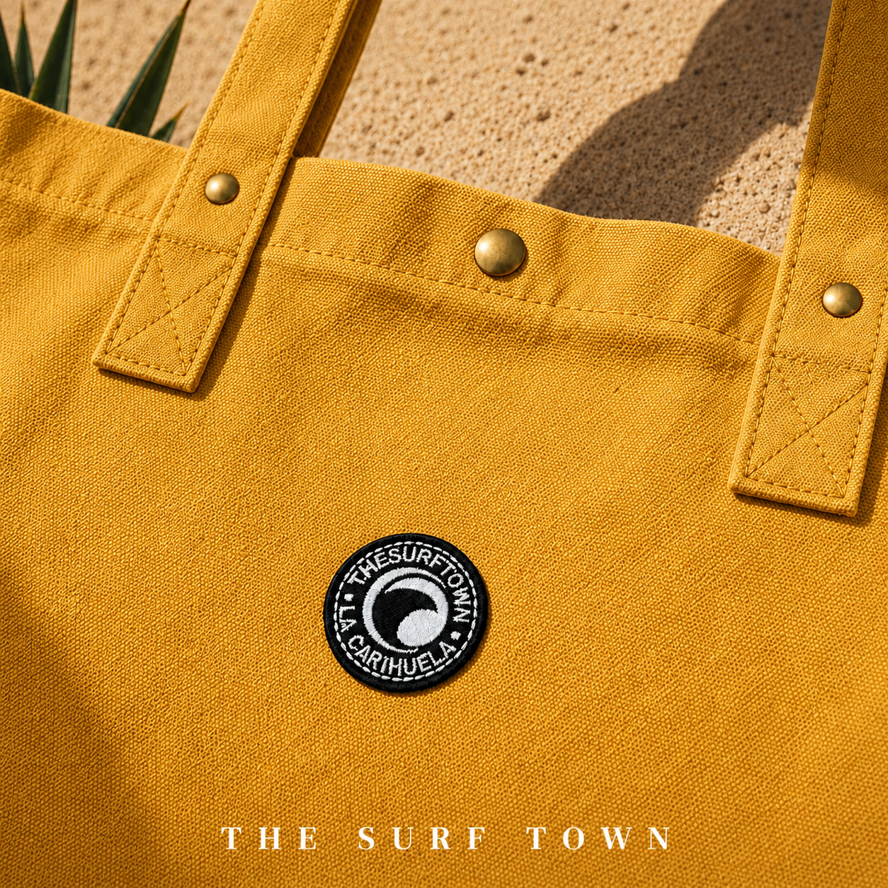 Detalle del parche del Bolso de Playa The Surf Town Tote Beach Bag Mustard de algodón color mostaza con gran capacidad y diseño exclusivo para playa y verano