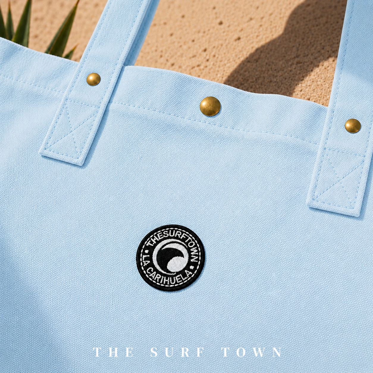 Detalle del parche bordado del bolso The Surf Town Tote Beach Bag Blue Sky sobre tejido de algodón azul cielo resistente, fotografía propia de THE SURF TOWN