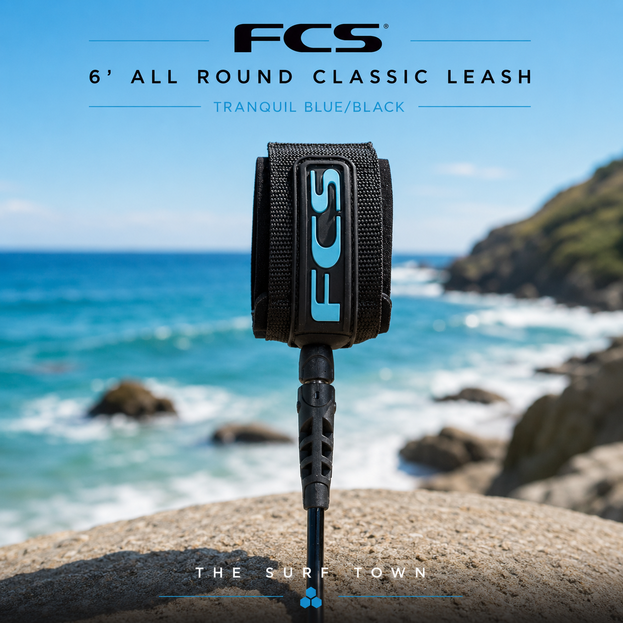 Leash FCS 6' All Round Classic Leash Tranquil Blue Black en fotografía editorial propia de THE SURF TOWN con ambiente surf premium, mar azul, luz diurna y fondo costero desenfocado para destacar el producto.