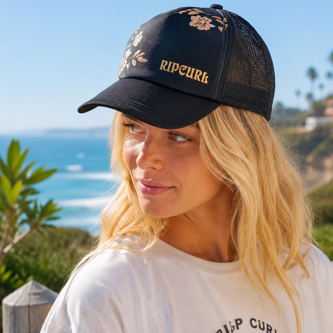 Gorra Rip Curl Trucker Mixed Black en acantilados junto al mar con estética surf lifestyle femenina premium