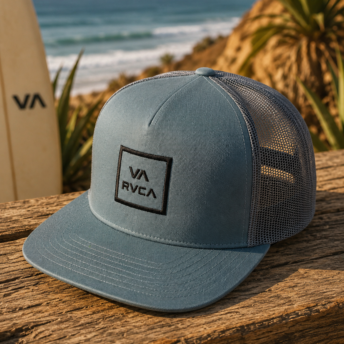 Gorra RVCA VA All The Way azul estilo surf lifestyle sobre mesa de madera junto al mar