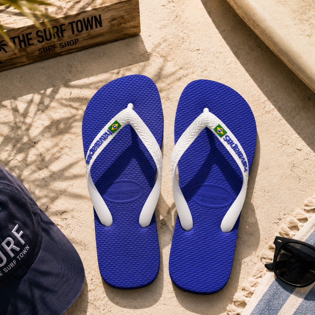 Chanclas Havaianas Brasil Logo azul naval sobre arena mediterránea junto a accesorios surf premium y detalle The Surf Town Surf Shop