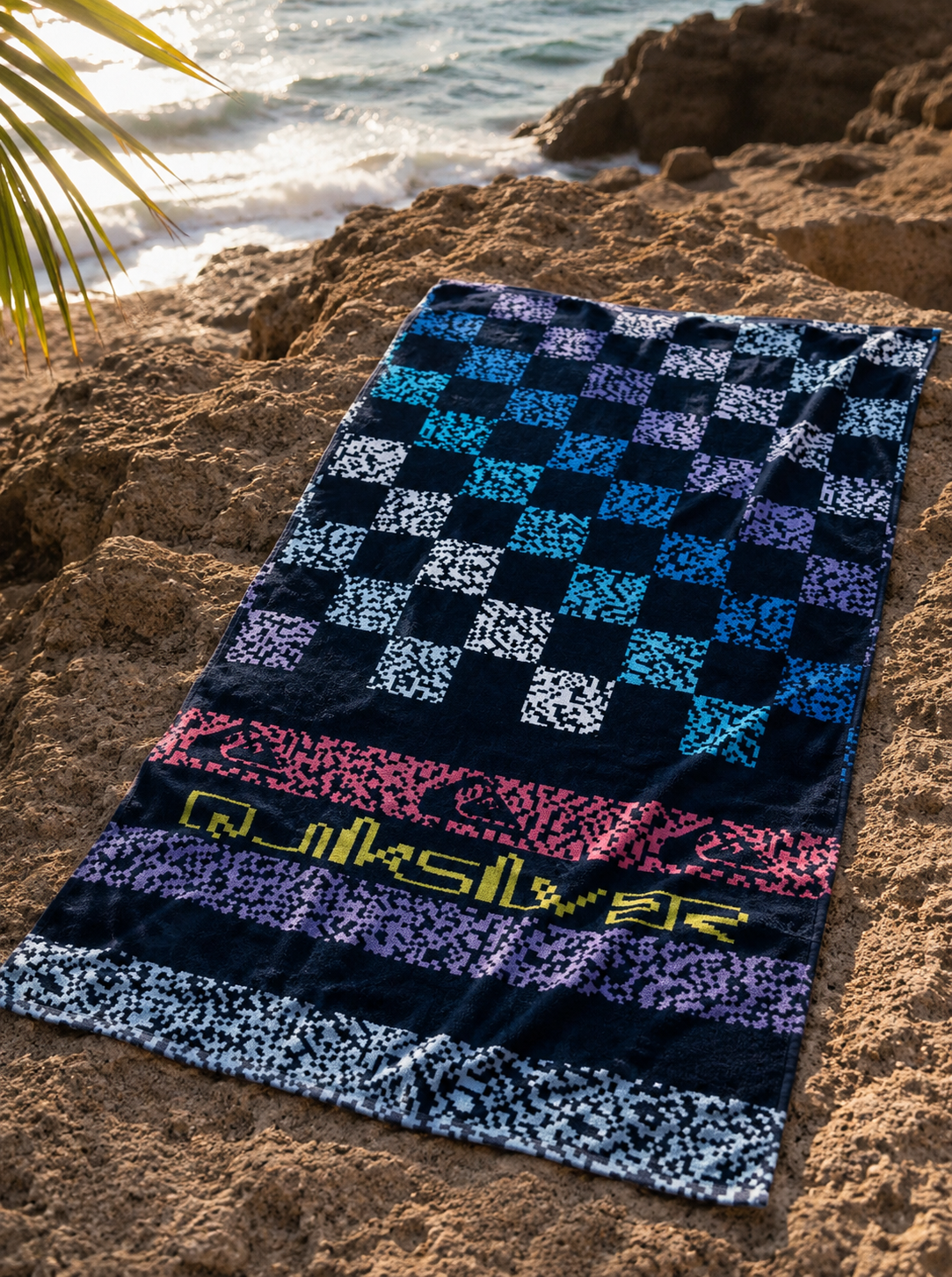 Toalla Quiksilver Freshness Dark Navy Next Gen estilo surf premium sobre rocas junto al mar
