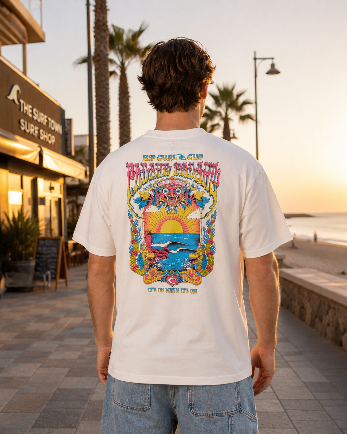 Camiseta blanca Rip Curl Padang Padang hombre en paseo marítimo surf lifestyle premium al atardecer Costa del Sol
