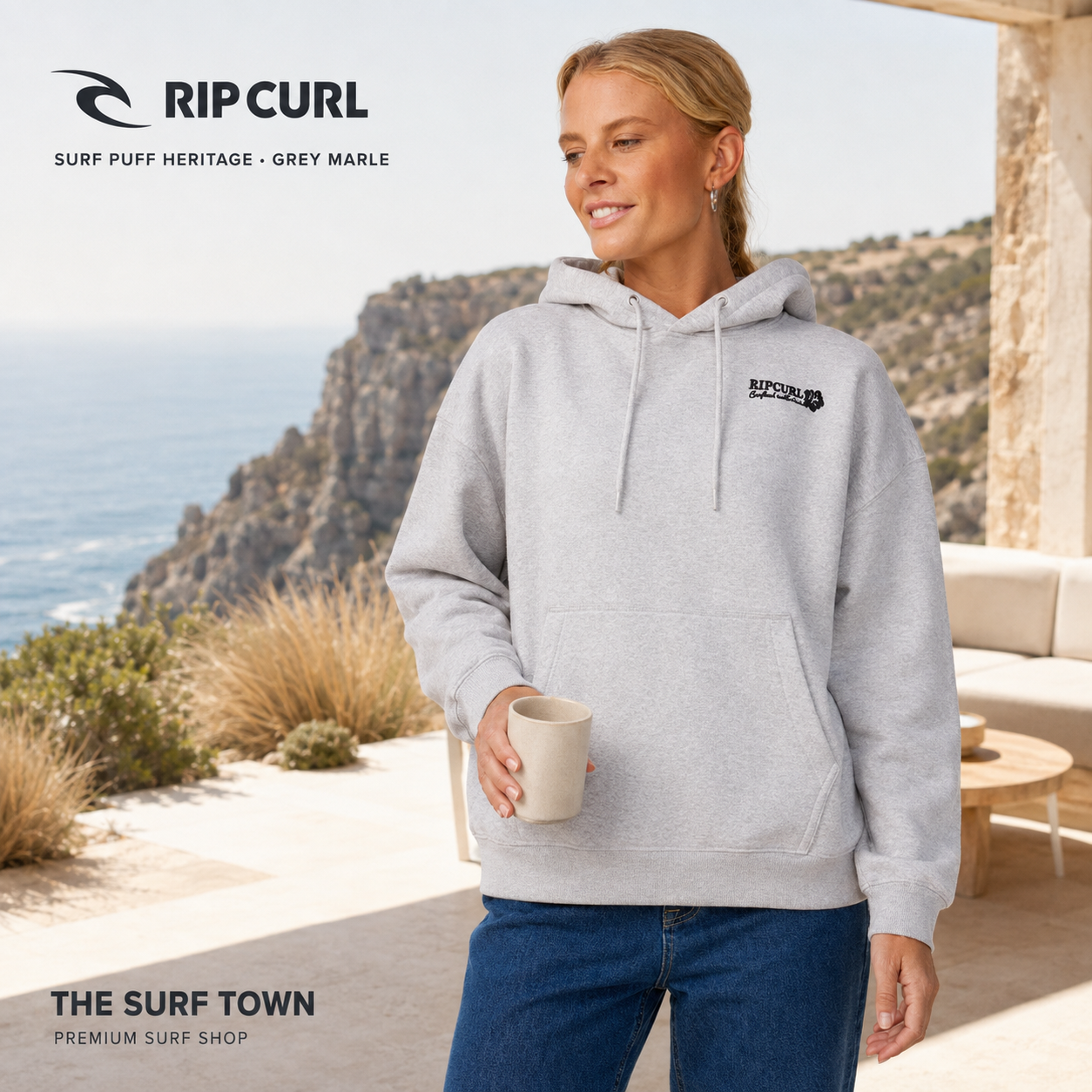 Sudadera de mujer Rip Curl Surf Puff Heritage Grey Marle con capucha y logo frontal, en una imagen editorial propia de THE SURF TOWN en una terraza costera.