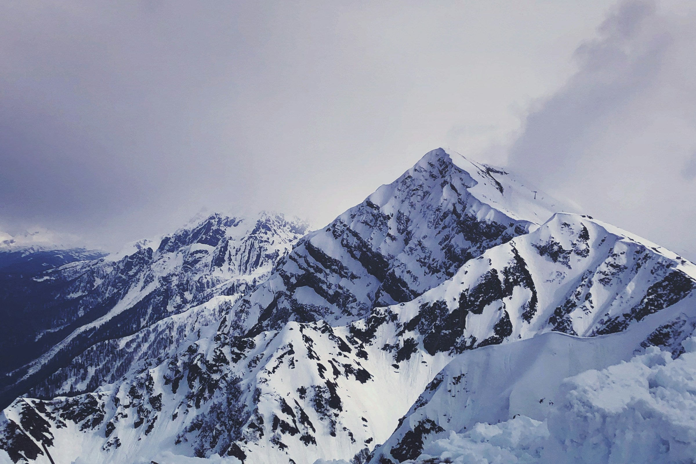 Snowboarder sobre una cresta nevada ajustando su equipo