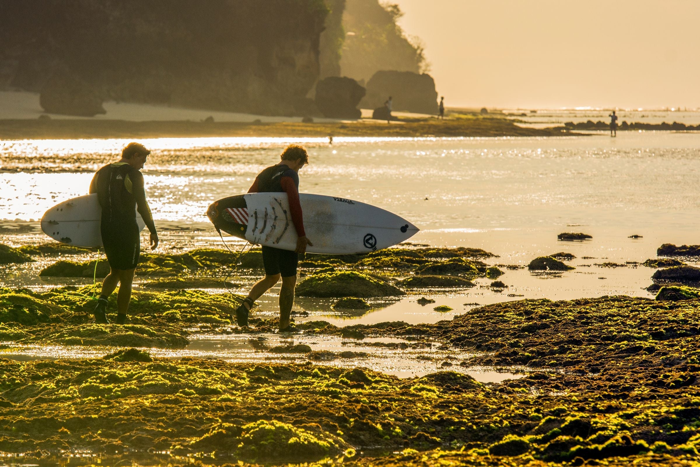 Dos surfistas caminan hacia el mar al amanecer en Bali