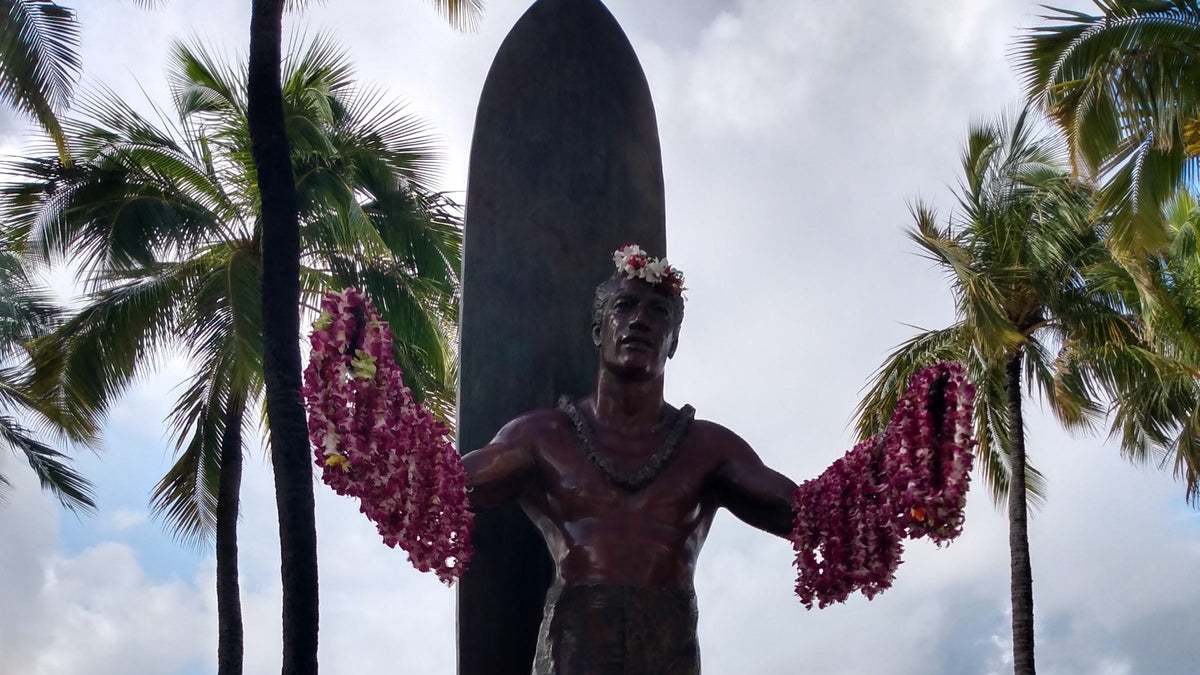 Duke Kahanamoku sobre una tabla de surf en fotografía histórica