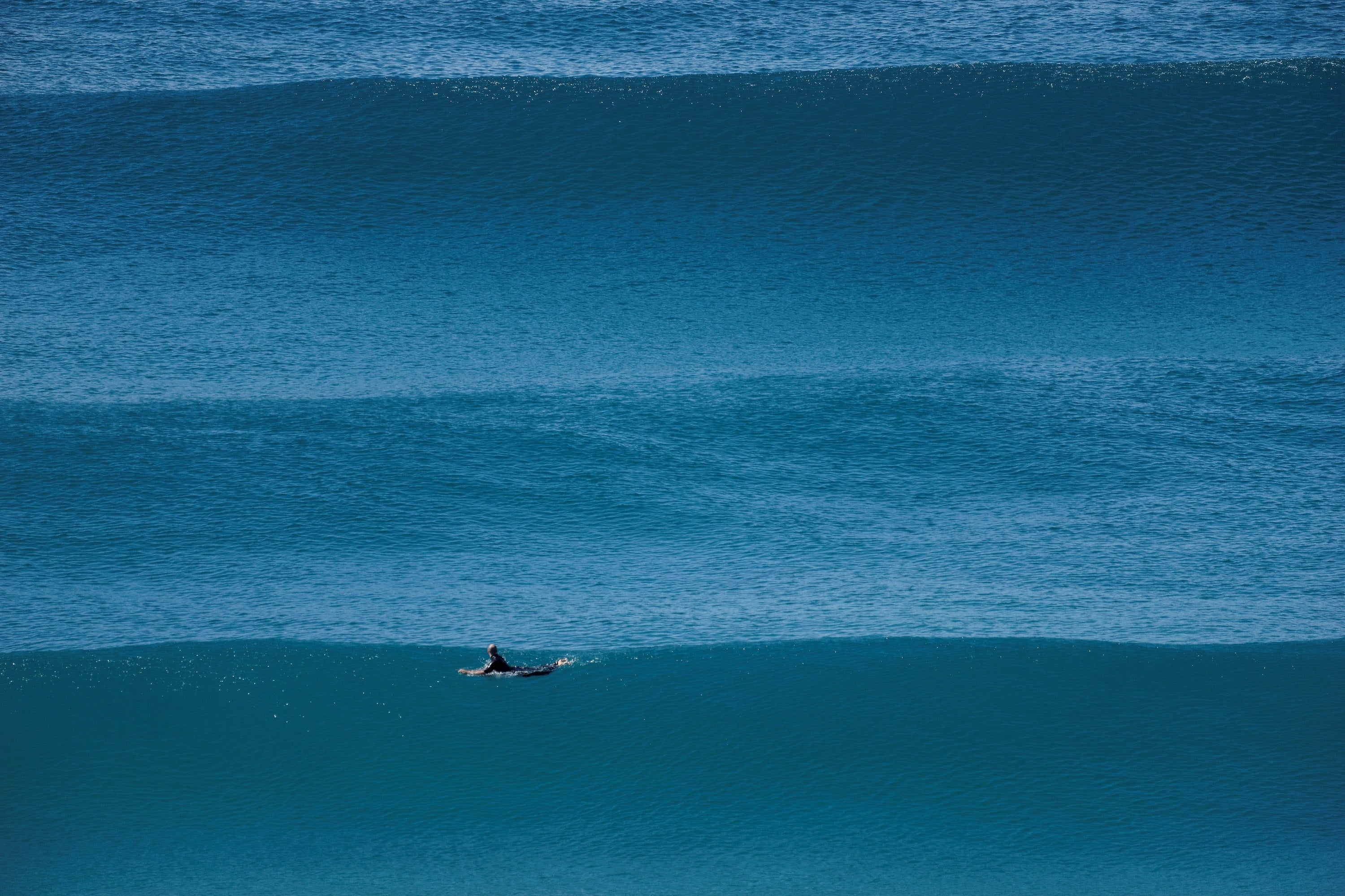 Surfista remando entre líneas de olas durante una sesión en el mar. Foto: bigwavephoto / Wikimedia Commons, CC BY-SA 4.0.