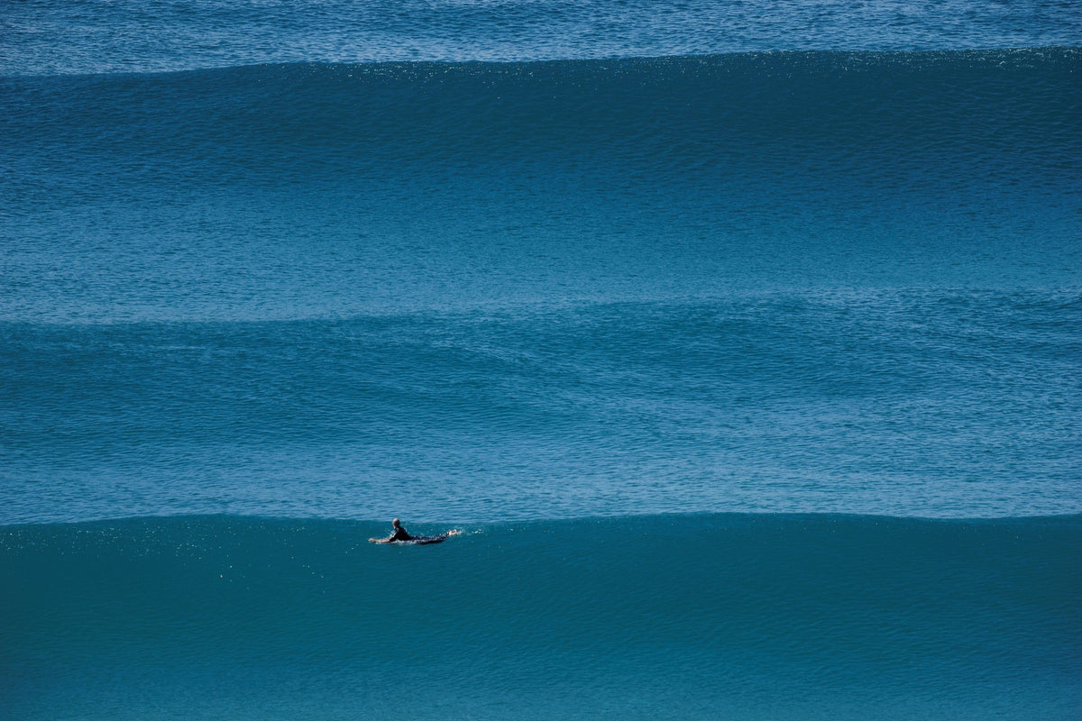 Surfista remando entre líneas de olas durante una sesión en el mar. Foto: bigwavephoto / Wikimedia Commons, CC BY-SA 4.0.