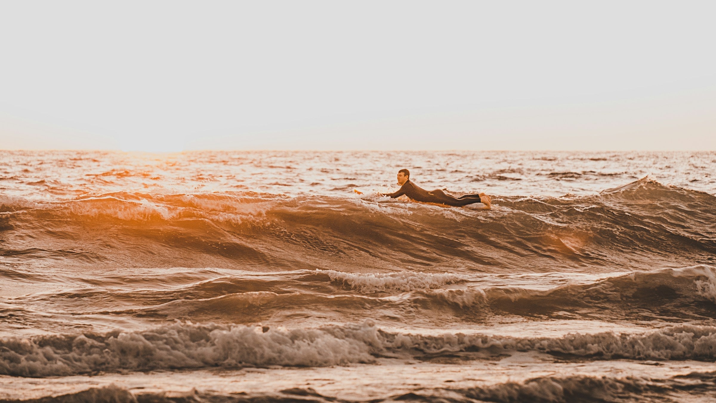 Surfista sobre una ola durante el amanecer