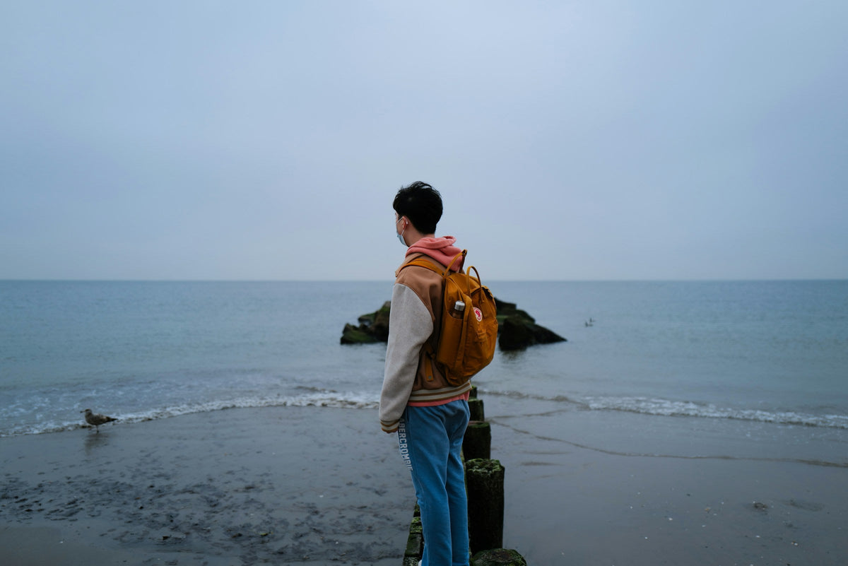 Viajero con mochila frente al mar durante una escapada costera