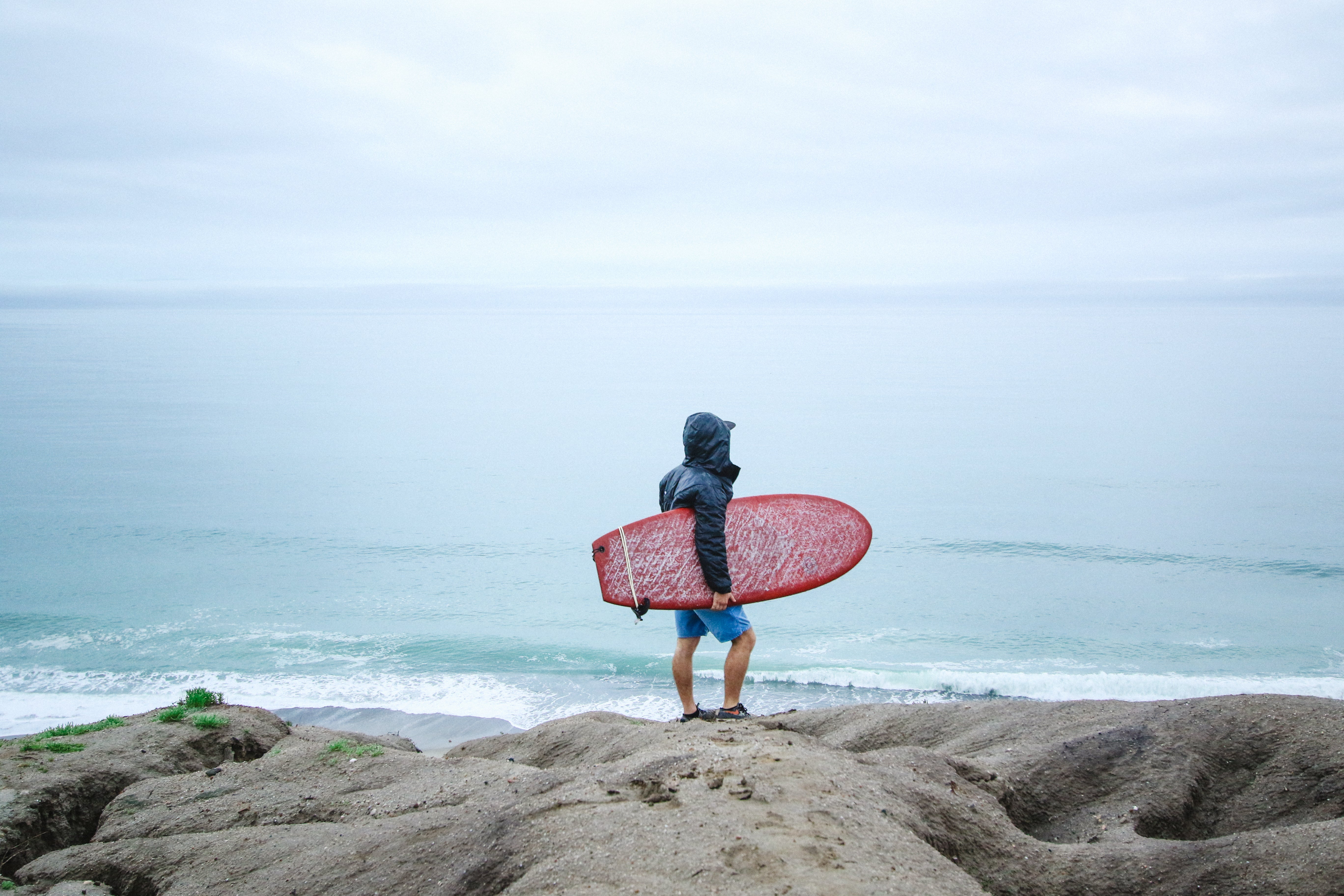 Surfista con capucha de neopreno frente al mar en San Clemente