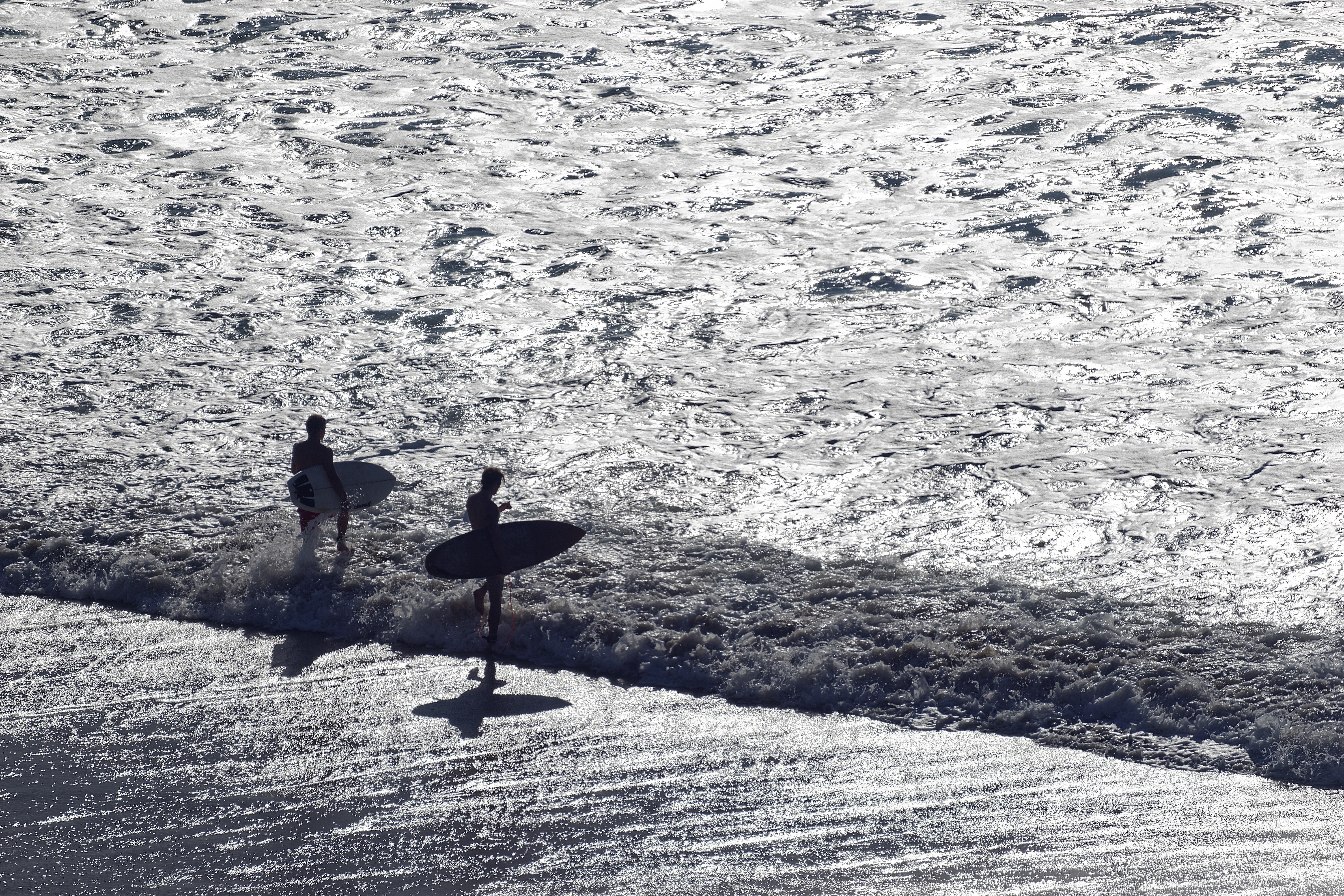 Dos surfistas entrando al agua con luz de amanecer