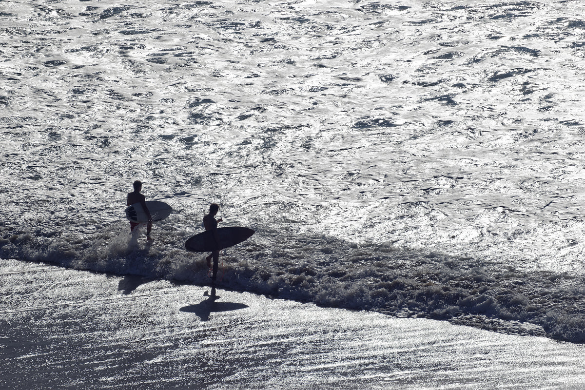 Dos surfistas entrando al agua con luz de amanecer