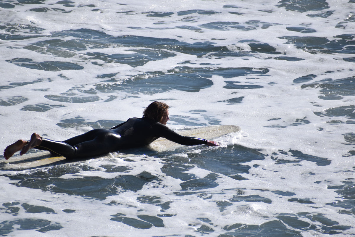 Surfista remando hacia una serie de olas