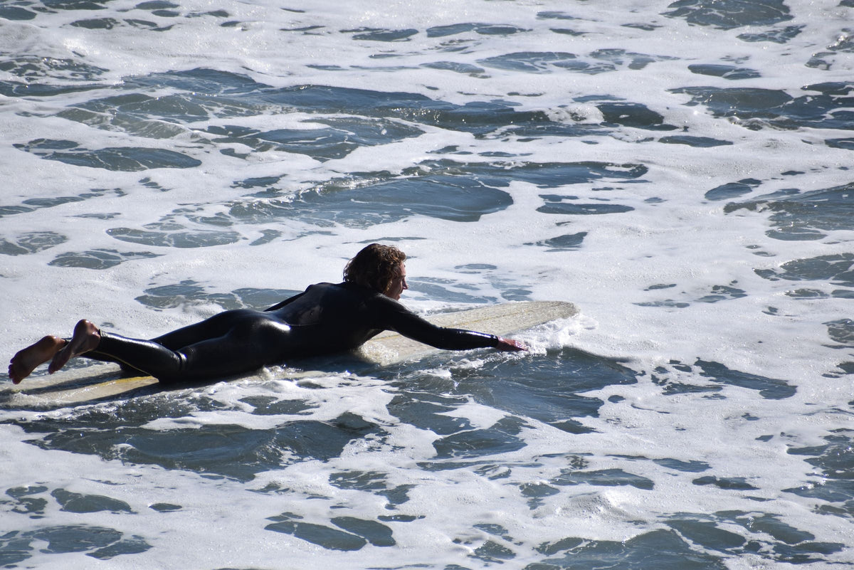 Surfista remando sobre una tabla entre olas abiertas