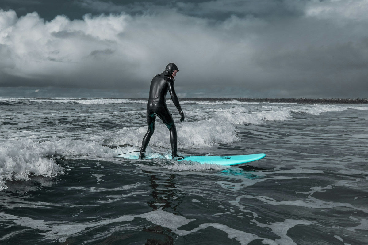 Surfista en el agua bajo un cielo cubierto después de la lluvia