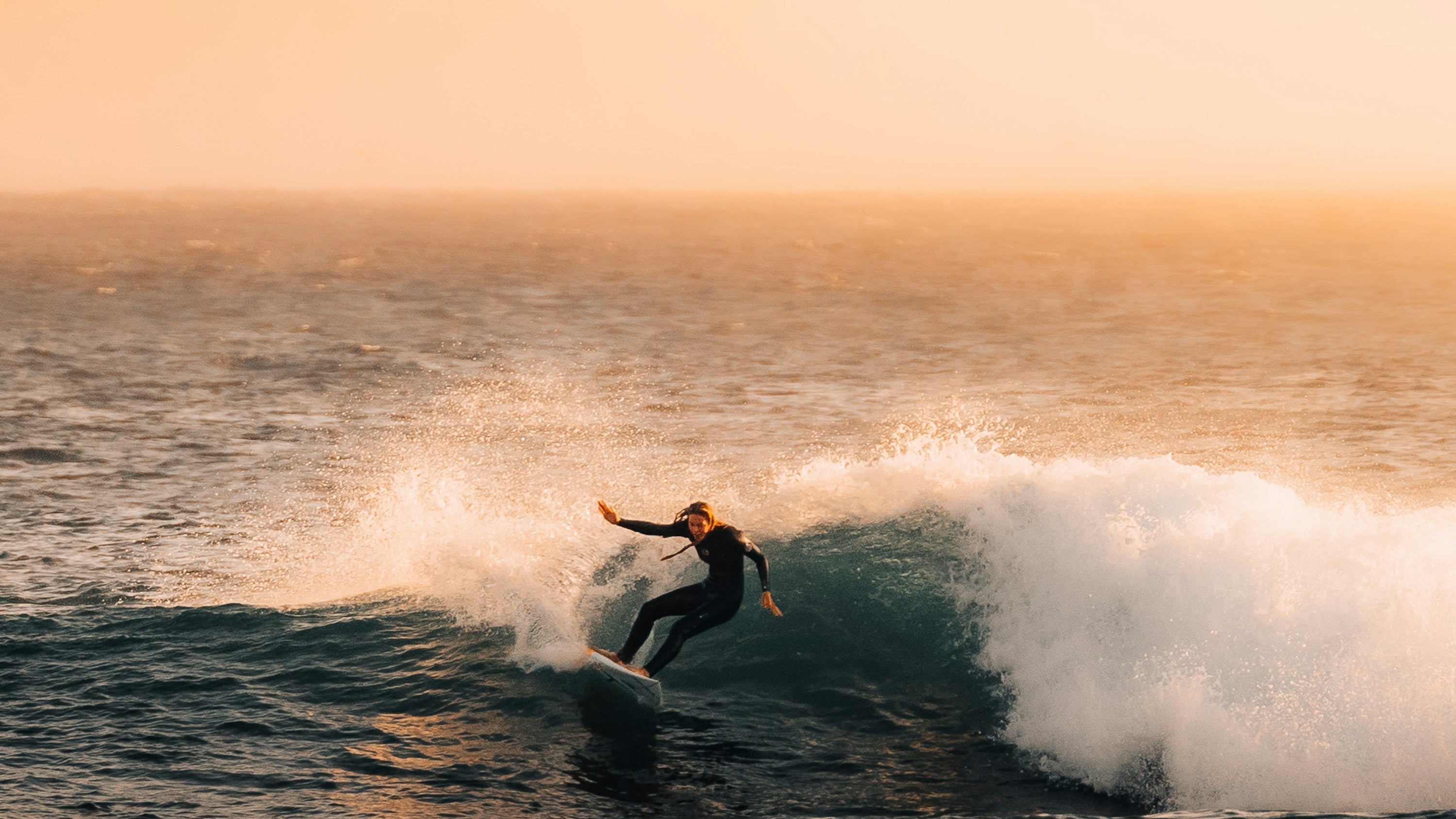 Surfista sobre una ola con luz baja de otoño