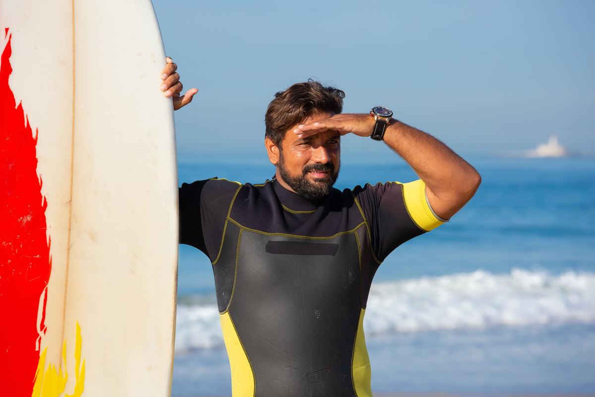 Surfista protegiéndose del sol junto a su tabla en la costa de Portugal